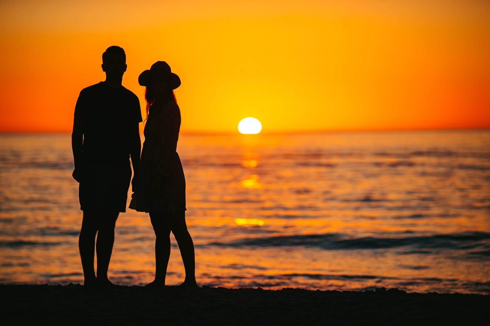 Silhouette of a couple watching the sunset on a beach