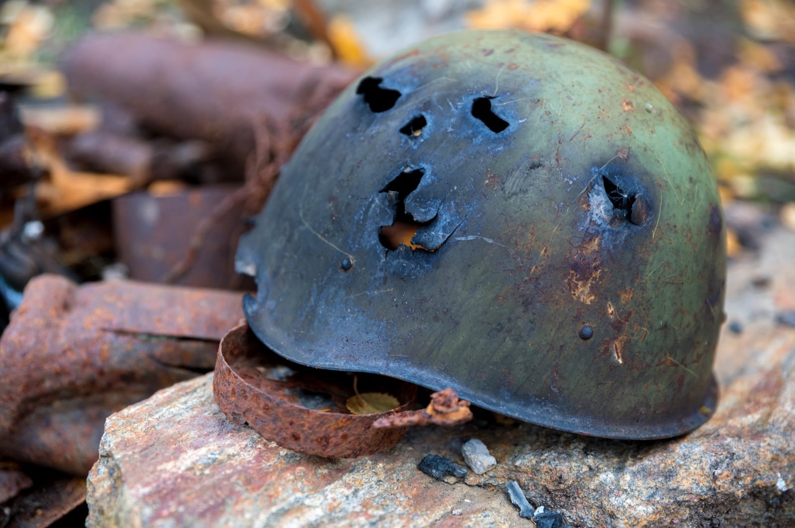 Damaged military helmet resting on a rock outdoors