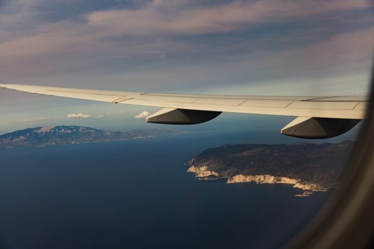View from an airplane window over the wing, with sea and coastline below