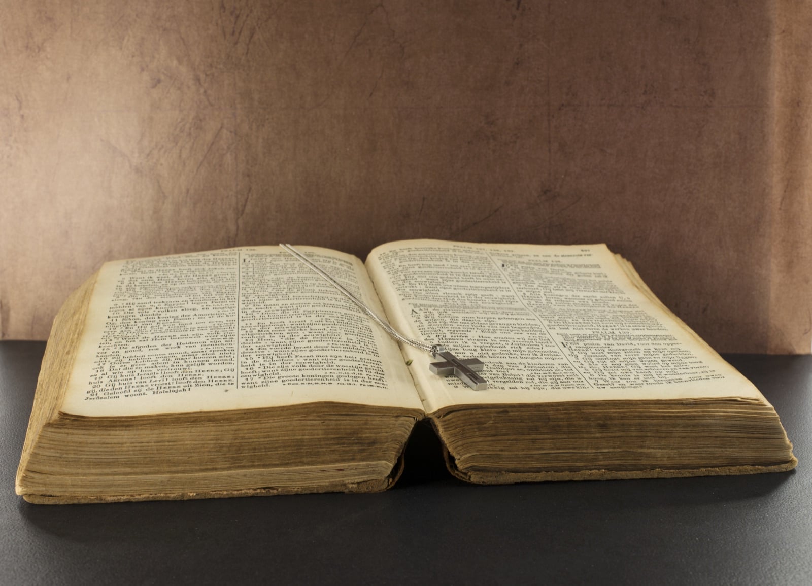 Open Bible with a silver cross necklace on a table, recalling Kristoforidhi's Albanian Bible translations