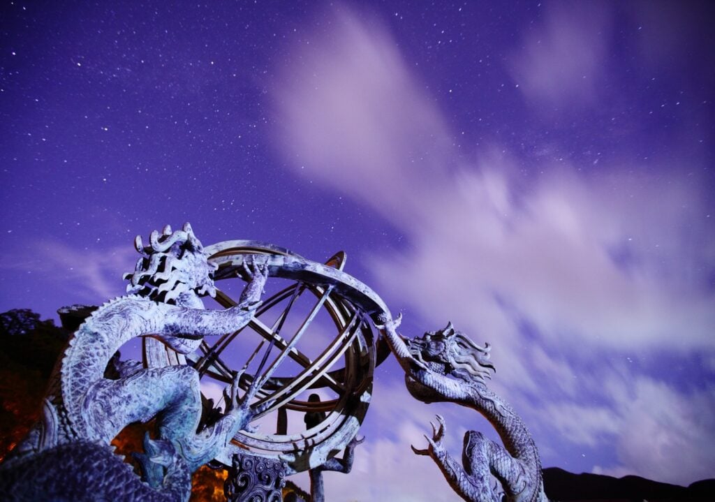 Dragon sculpture under a cloudy night sky, evoking the kulshedra of Albanian mythology