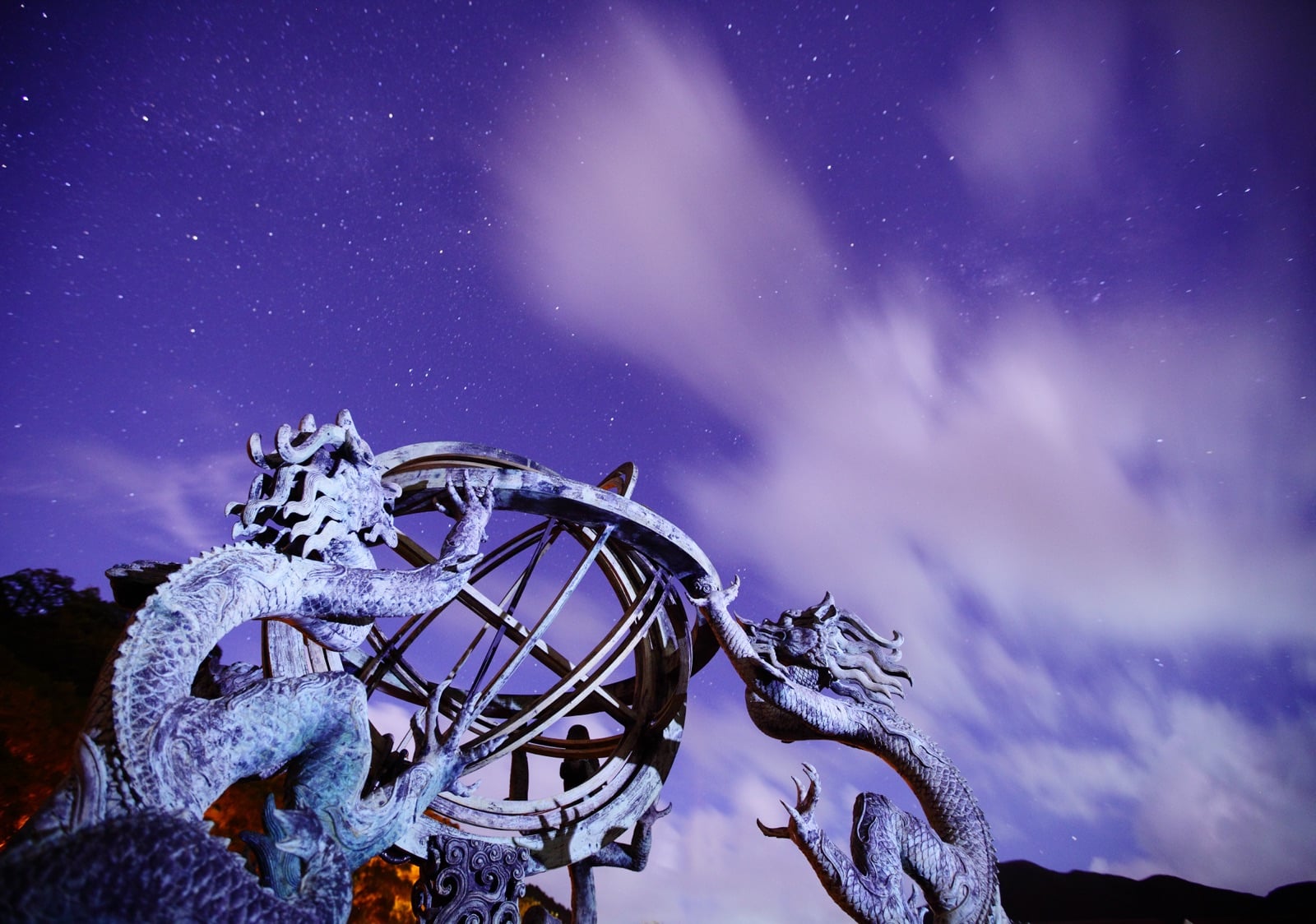 Dragon sculpture under a cloudy night sky, evoking the kulshedra of Albanian mythology