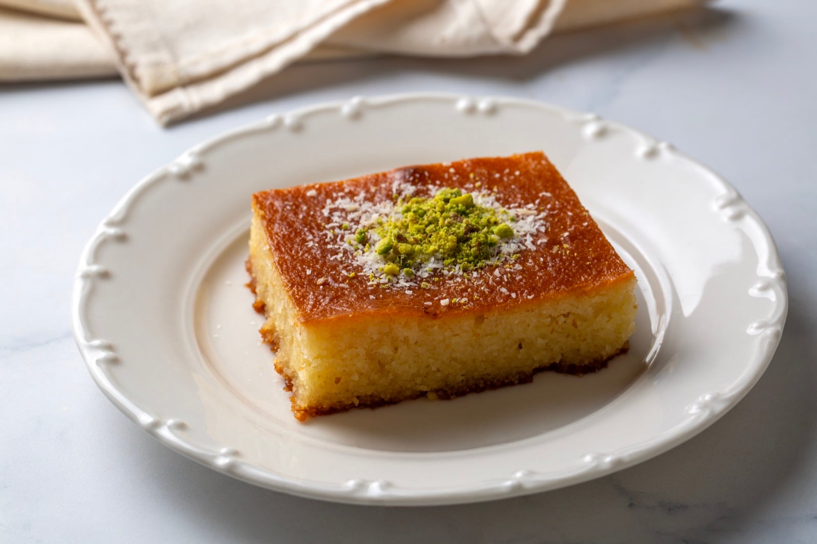 Square of revani, Albanian semolina cake soaked in syrup, topped with pistachios and coconut