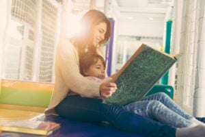 Woman reading a book to a child sitting on her lap